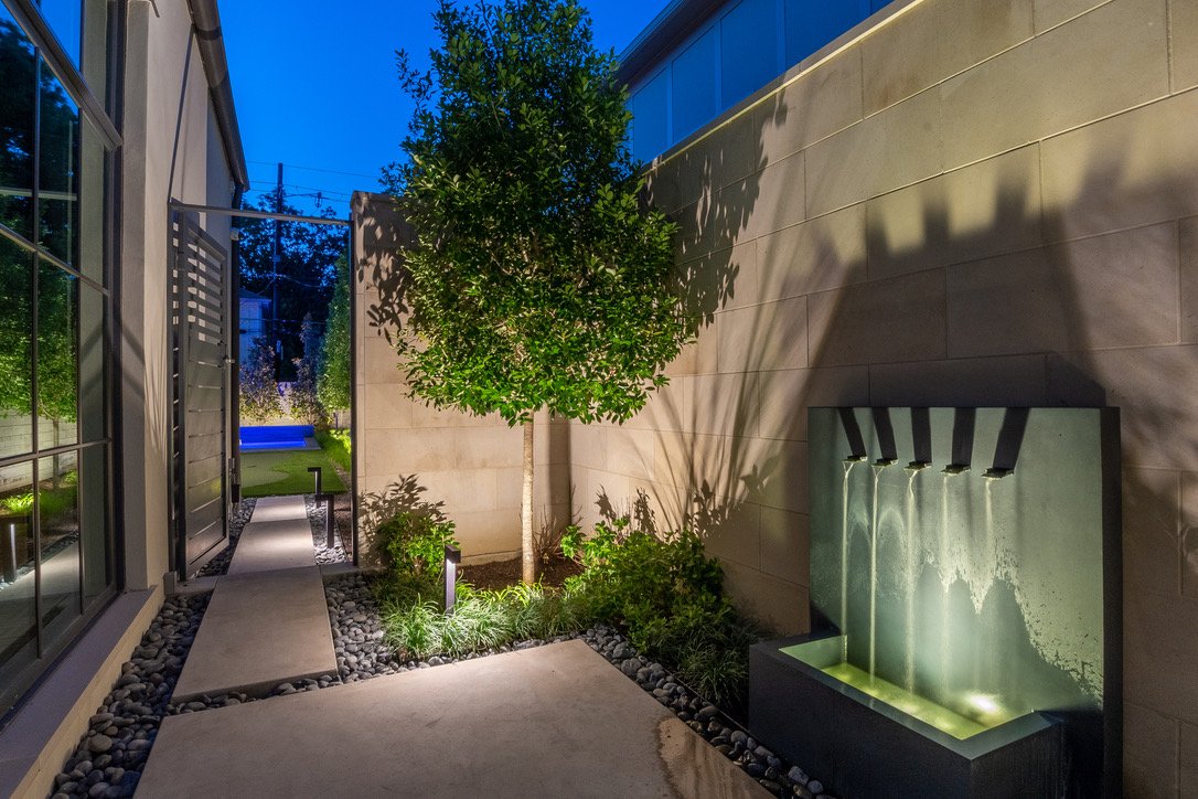 Modern home exterior with landscape lighting on a tree and garden bed