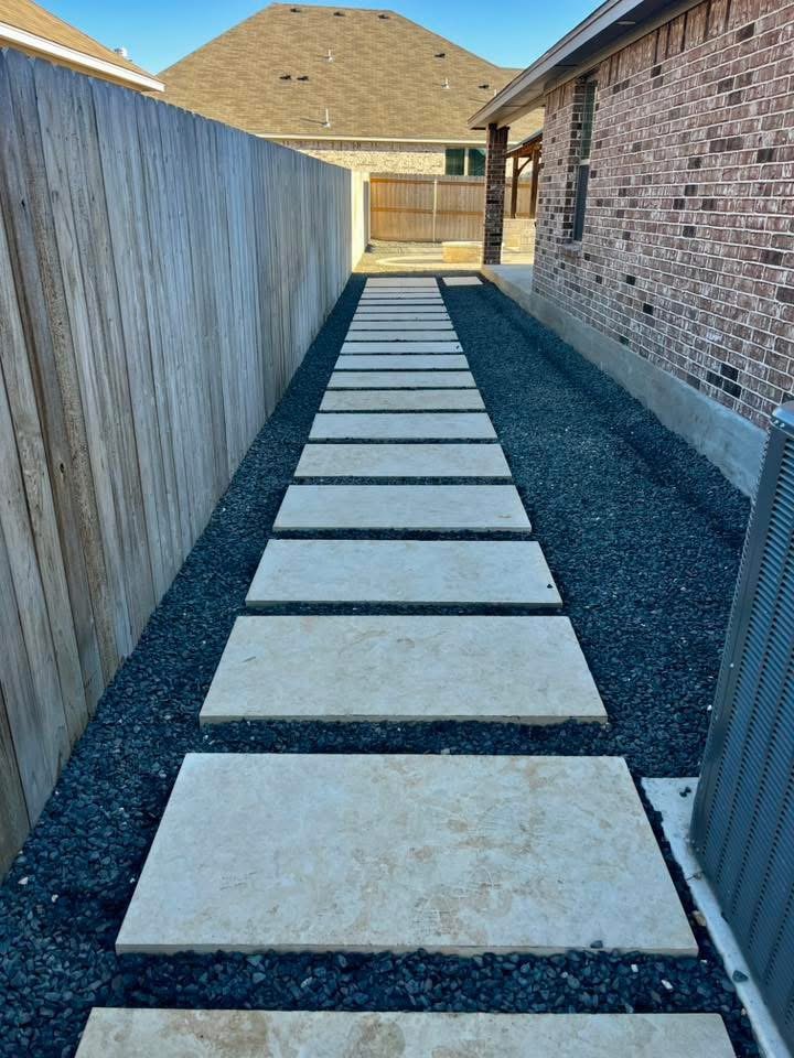 Stepping-stone path with black rock along a side yard fence