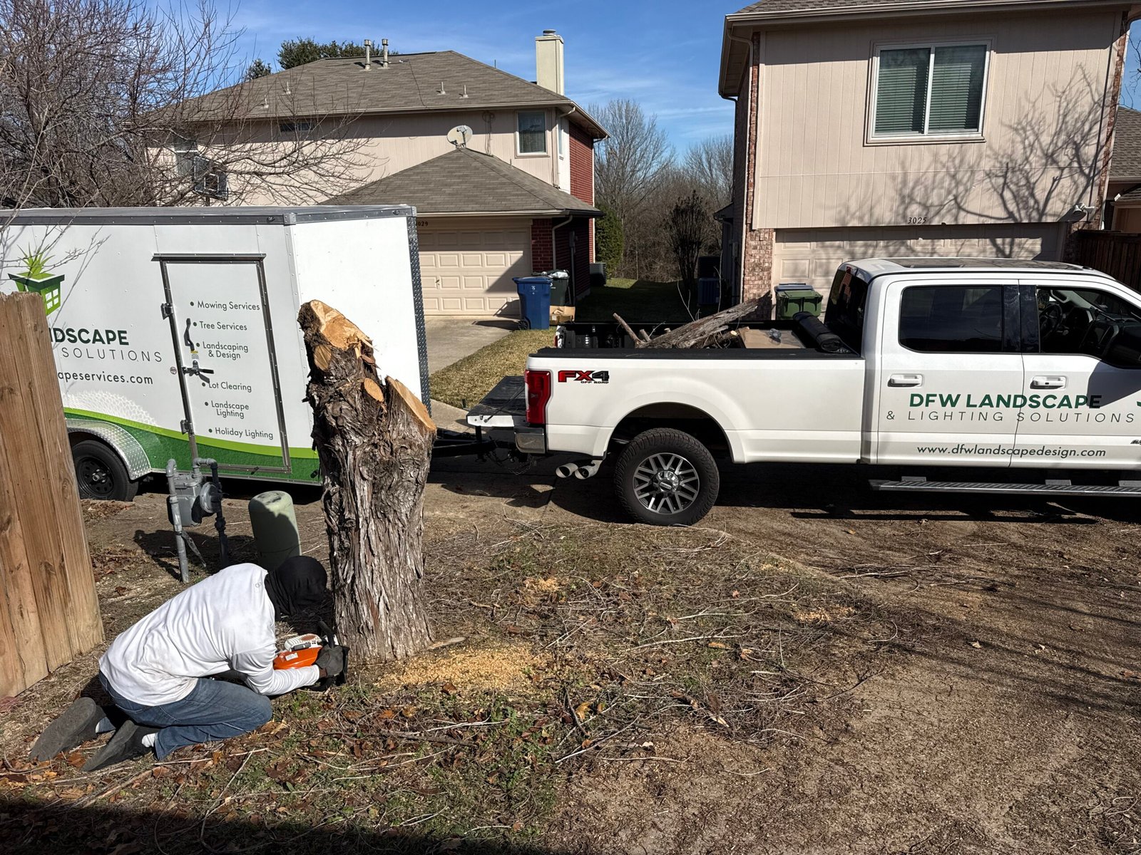 Tree removal in progress with work truck and trailer at a home