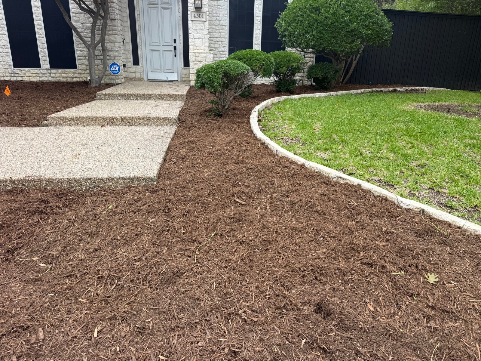 Fresh mulch bed with curved edging along a front lawn