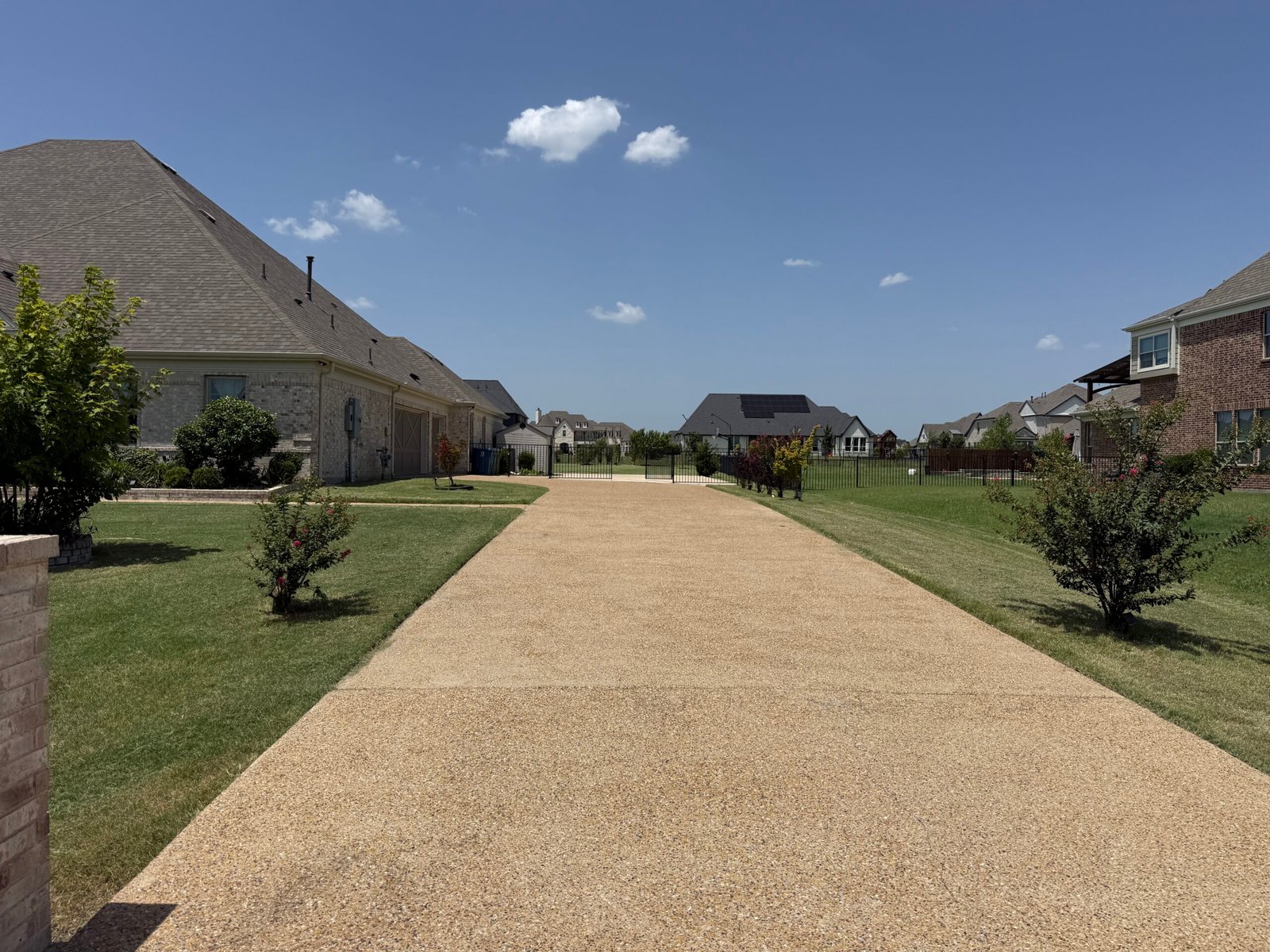 Exposed aggregate driveway lined by green lawn