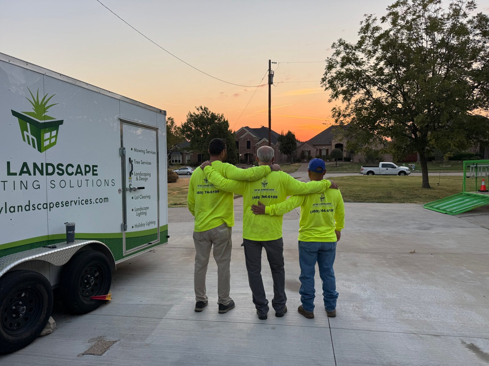 DFW Landscape & Lighting Solutions crew beside their work trailer at sunset