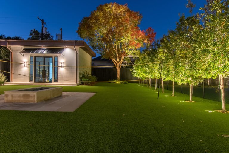 Outdoor landscape lighting around a home and trees at dusk