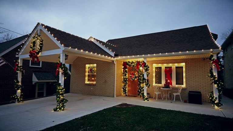 Home with holiday roofline lights and garland-wrapped porch columns